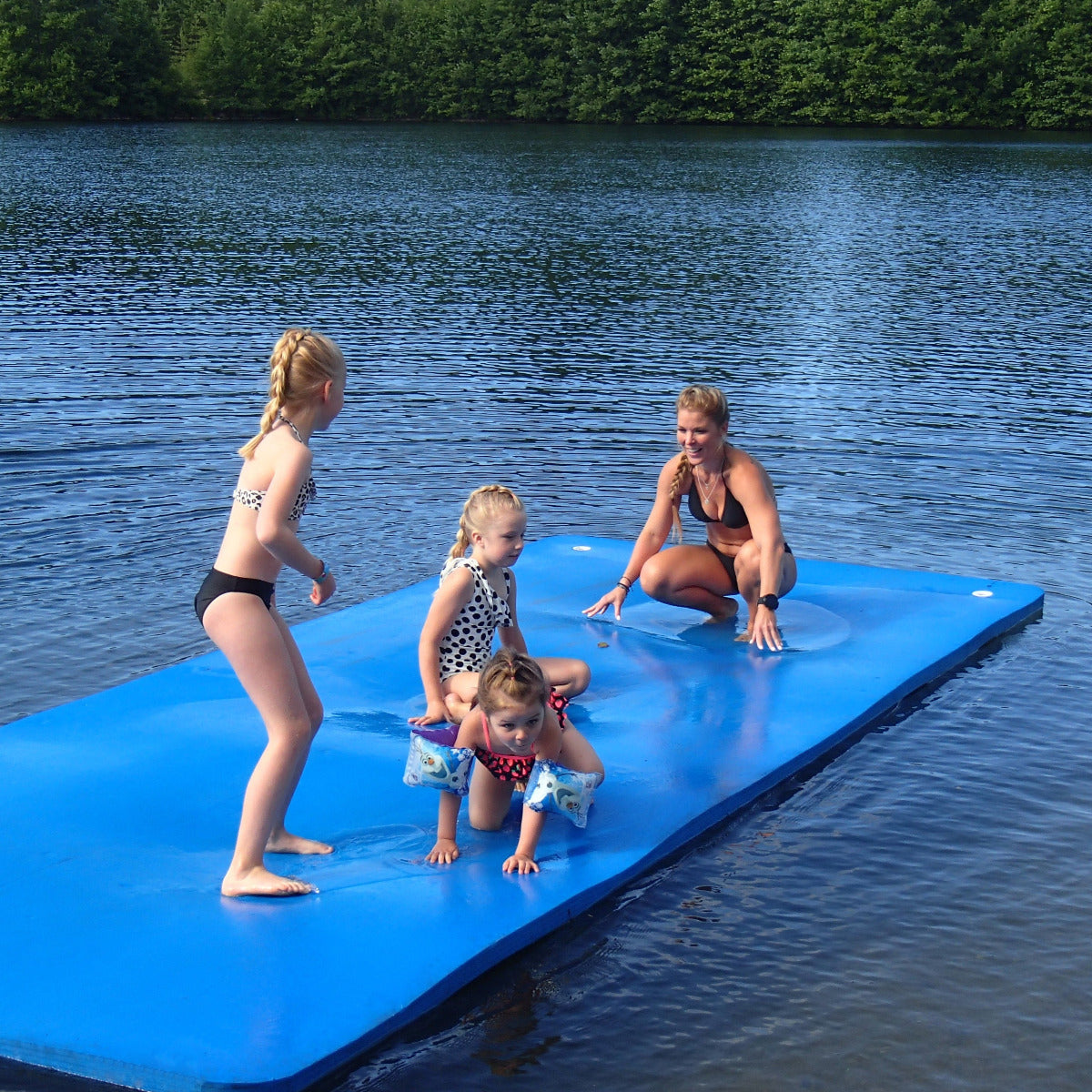 Perhe vedessä kelluvan maton päällä