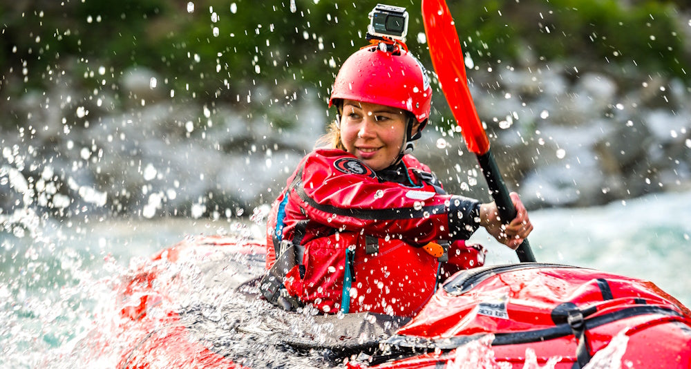 Nainen meloo punaista packraftia Ursuitin kuivapuvussa
