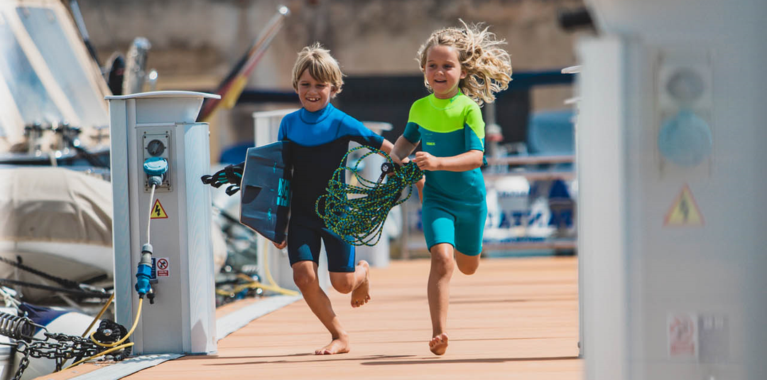 Lapset märkäpuvuissa venelaiturilla