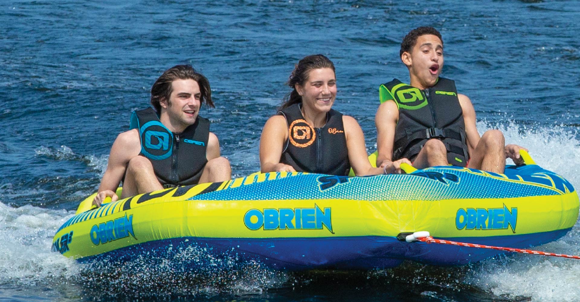 Kolme henkilöä kelluntaliiveissä vetorenkaan päällä